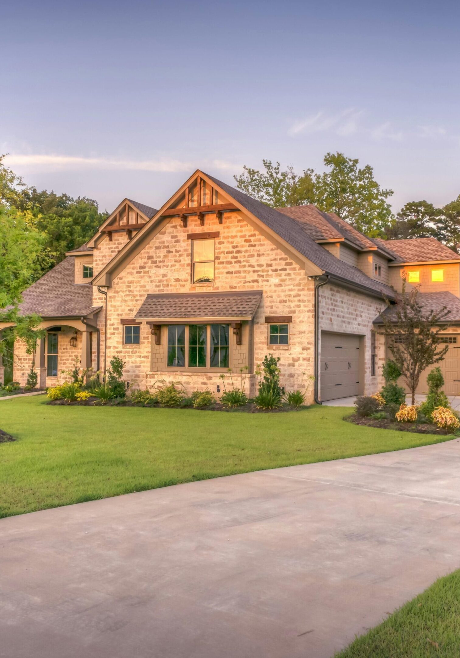 A charming stone house with a steep roof and lush green lawn.